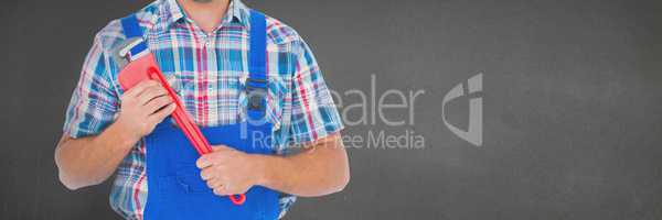 Mechanic man holding a wrench against grey background