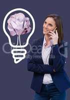 Woman on phone standing next to light bulb with crumpled paper ball