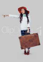 Full body portrait of woman standing and holding suitcase with grey background