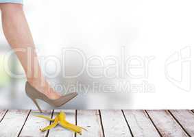 Woman's foot stepping on banana on wood