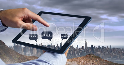 Holding tablet and Chat bubble icons over city