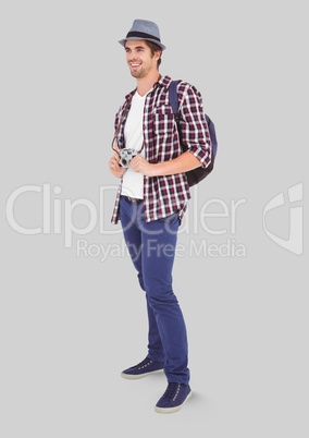 Full body portrait of Man standing with grey background and backpack and camera