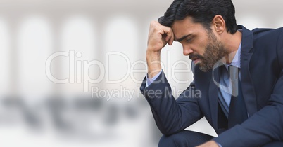 Worried business man sitting against office background