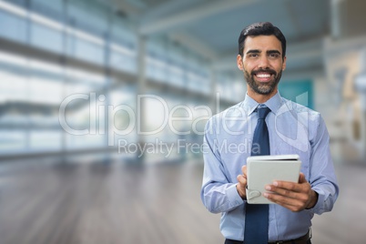 Happy business man using a tablet against office background