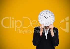 Woman holding clock in front of yellow background