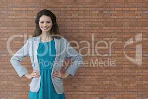 Happy business woman standing against brick wall background