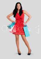 Full body portrait of woman standing and holding shopping bags with grey background