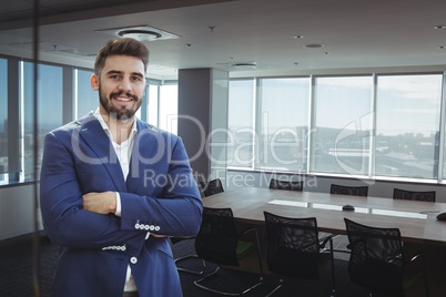 Happy business man standing against office background