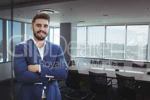 Happy business man standing against office background