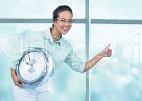 Woman holding clock in front of windows