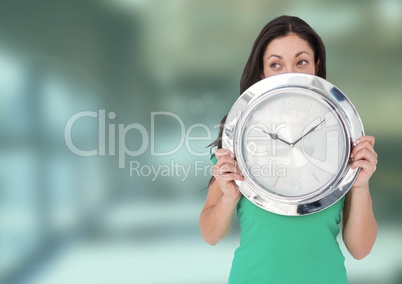 Woman holding clock in front of green blur