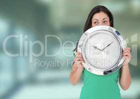 Woman holding clock in front of green blur