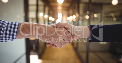 Business people shaking hands against office background