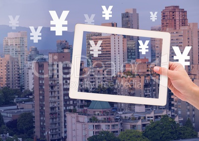 Holding tablet and Yen icons over city buildings