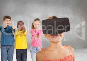 Kids pointing at girl with VR headset in grey room
