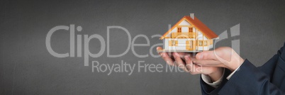 Person holding a house against grey background as house insurance concept