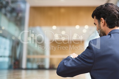 Business man looking at his clock against office background