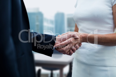 Business people shaking hands against office background