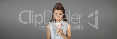 Young woman drinking a milkshake against wide blank grey