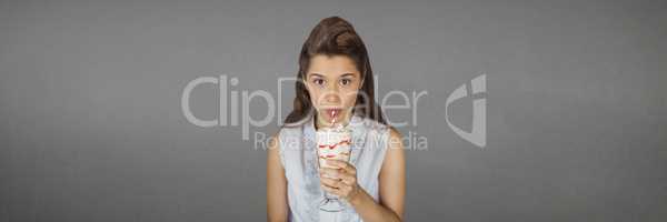 Young woman drinking a milkshake against wide blank grey