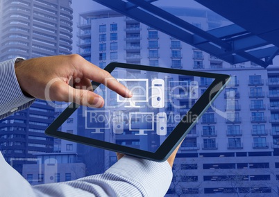 Holding tablet and Computer icons over city