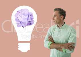 Man standing next to light bulb with crumpled paper ball