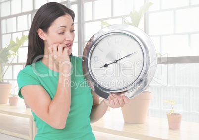 Woman holding clock in front of windows