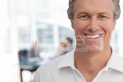 Happy business man standing against office background