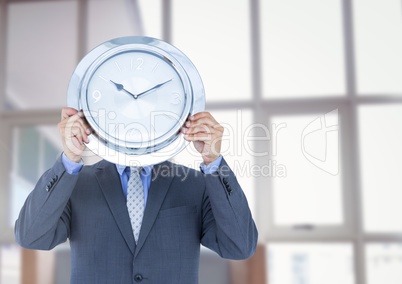 man holding clock in front of windows