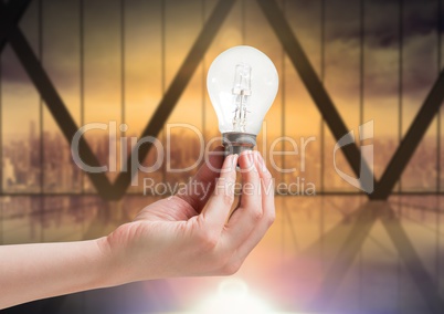 Hand holding light bulb by windows