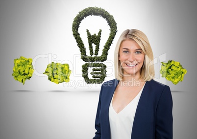 Woman standing next to green nature light bulb with crumpled paper balls