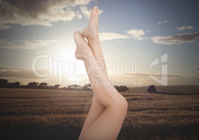 Woman's slim legs posing upside down in front of nature field