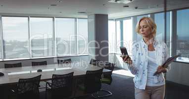 Business woman looking at a phone against office background