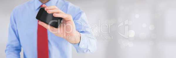Business man holding a phone against grey background with lights