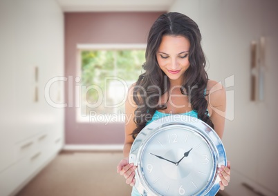 Woman holding clock in front of room window