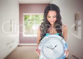 Woman holding clock in front of room window
