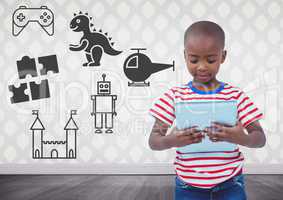 Boy holding tablet in blank room with toys graphics