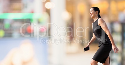 Excited business woman walking against background with lights