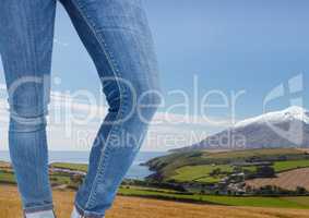 Woman's legs in jeans in front of nature landscape