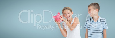 Happy boy and happy girl holding a piggy bank against blue background