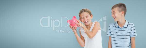 Happy boy and happy girl holding a piggy bank against blue background