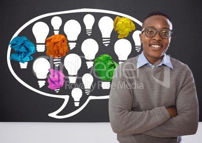 Man standing next to light bulbs chat bubble with crumpled paper balls in front of blackboard