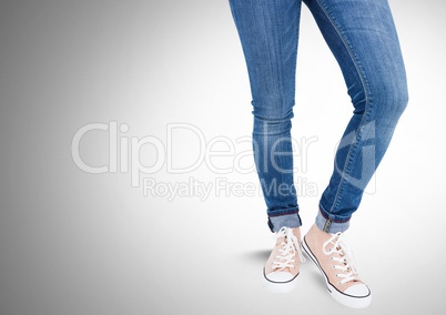 Woman's legs in jeans in front of grey background