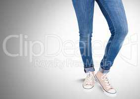 Woman's legs in jeans in front of grey background