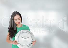 Woman holding clock in front of bright blurred background