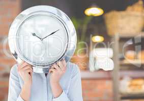 Woman holding clock in front of cafe