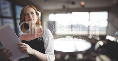 Confused business woman holding files against office background