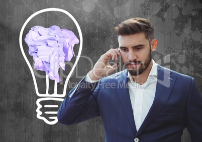 Man on phone standing next to light bulb with crumpled paper ball