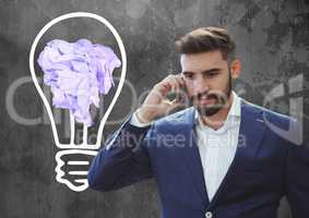Man on phone standing next to light bulb with crumpled paper ball