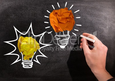 Hand drawing light bulbs on blackboard with chalk and crumpled paper balls